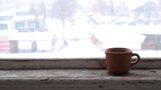 Time lapse of cars moving on city road in winter with a cup on window sill. View from old wooden window.