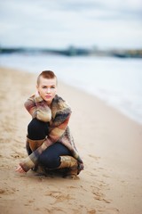 Beautiful, confident, girl with short hair squatted on the banks of the Neva. The concept of youth fashion