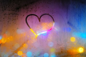 Abstract background - heart drawn on a steamed up window on the background of colorful city lights at night