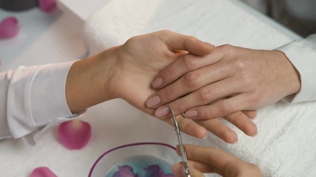Manicure. Closeup Of Manicurist Hands Removing Cuticle From Female Nails With Professional Metal Nail Scissors. Woman Hand With Healthy Natural Nails Getting Nails Care Procedure. High Resolution