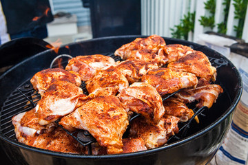 Seasoned grilled chicken cooking on barbecue in summer