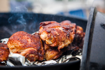 Seasoned grilled chicken cooking on barbecue in summer