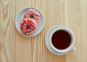 Delicious donuts with cup of tea on wooden background