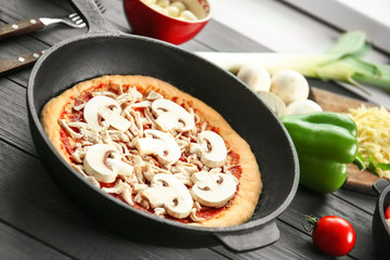 Unbaked pizza in pan on wooden table