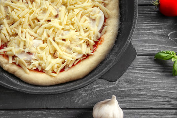 Unbaked pizza in pan on wooden table