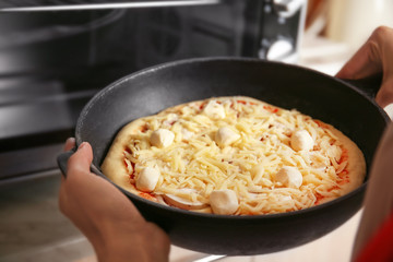 Woman putting pizza into oven