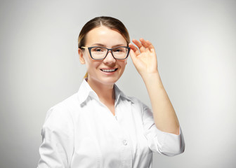 Young woman with spectacles on grey background