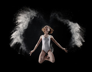 Little cute girl dancing with white powder on black background