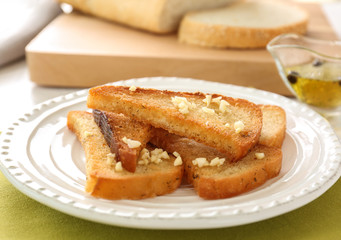 Plate with tasty garlic French bread slices on napkin