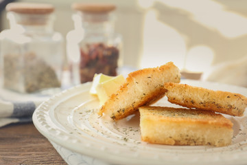 Plate with tasty garlic French bread slices on wooden table