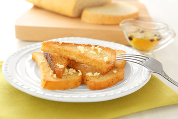 Plate with tasty garlic French bread slices on napkin