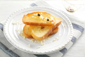 Plate with tasty garlic French bread slices on wooden table
