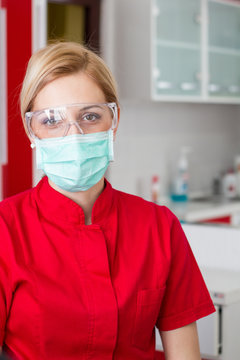 Dentist In A Red Uniform - Professional Doctor At Work With Mask And Glasses