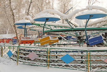 Сarousel seats covered with snow in amusement park in winter