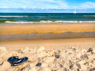 Fototapeta na wymiar Simple Life relaxing ocean water scene of flip flops lazily left on a quiet beach