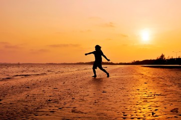 Fototapeta na wymiar Silhouette of girl running on the beach at sunset