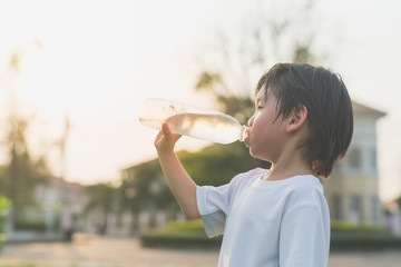 sian boy drinks water from a bottle © lalalululala