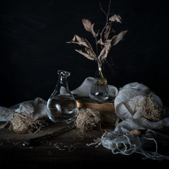 Still life with onions and dry leaves in a vase on a wooden table on a dark background