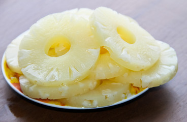 Canned pineapple on a plate on wooden table