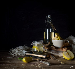 still life with apples, apple juice, old books and a silver knife on a wooden table on a dark background. vintage
