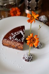 Obraz na płótnie Canvas Bright orange flower and chocolate dessert on the plate. Selective focus.