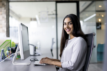 Portrait of happy female employee at computer