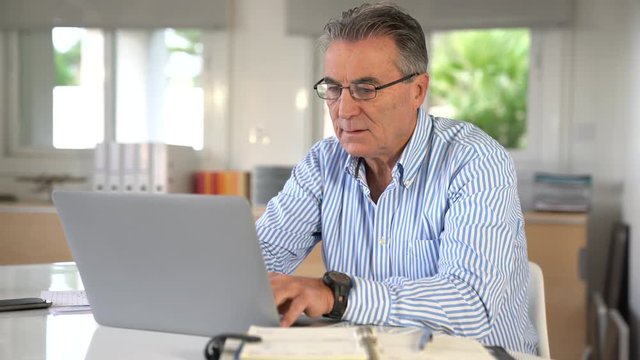 Senior man in office working on laptop computer