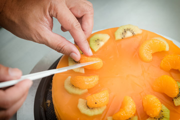 Chef decorating orange cake with fresh fruit