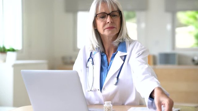 Portrait of senior doctor working on laptop