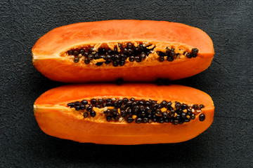 Papaya split in quarters top view on black