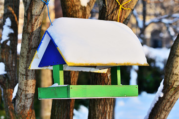 Wooden bird feeder in winter with snow