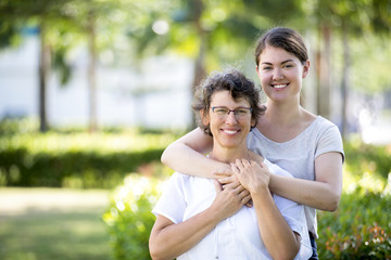 Happy teenage daughter embracing mother in park