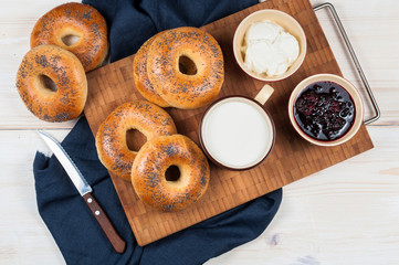 Fresh homemade Poppy bagels bread with cup of milk and berries j