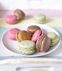 Delicious colorful macarons with cream. Coffee break scene with macaron candy and selective focus.
