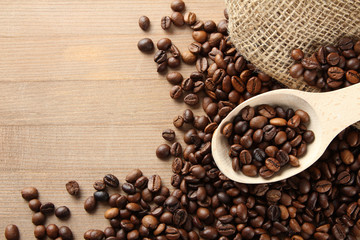 Handful of roasted coffee on a wooden table with a spoon.