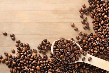 Handful of roasted coffee on a wooden table with a spoon.