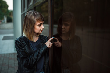 girl in a leather jacket looks at his reflection