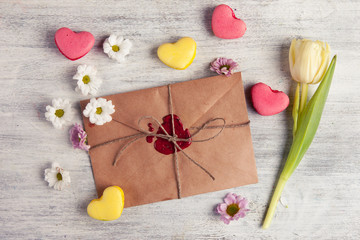 Envelope with wax seal and tulip on wooden background.