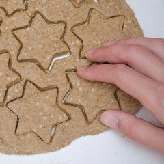 female hand take cutted Christmas cookies from rye dough with star shaped cutter