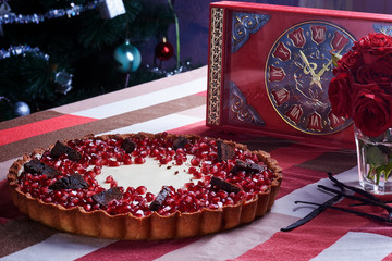 Tart with pomegranate on wood table.