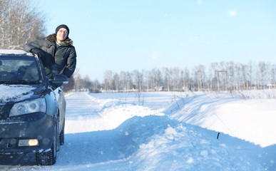 man looks out the car window at the snow-covered road in snow st