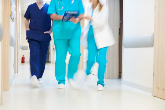 Doctors Walking Through Corridor In Hospital