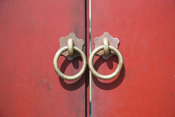 Ancient wooden gate with two door knocker rings close-up