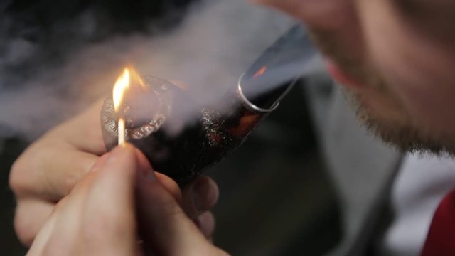 man in a suit ignites a smoking pipe. Close-up.