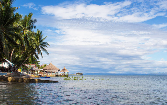 Seaside landscape with calm sea, coco palm trees lagoon and blue cloudy sky, fluffy cloud skyline