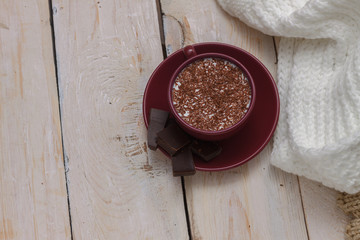 Milk chocolate in a cup on a saucer on a wooden background.