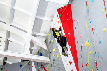 young caucasian man training at artificial rock climbing indoors