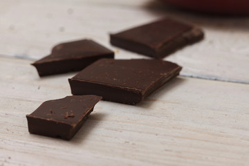 Milk chocolate in a cup on a saucer on a light wooden background