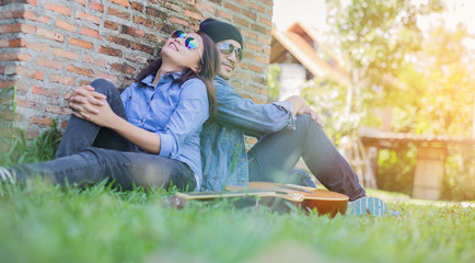 Hipster man playing guitar for his girlfriend outdoor against br