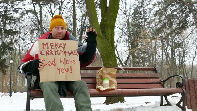 
4K.  Happy Homeless man in  winter city park with cardboard  Merry Christmas
